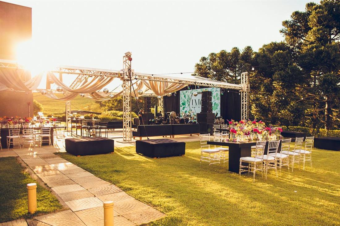Palco e mesas montados no gramado ao pôr do sol